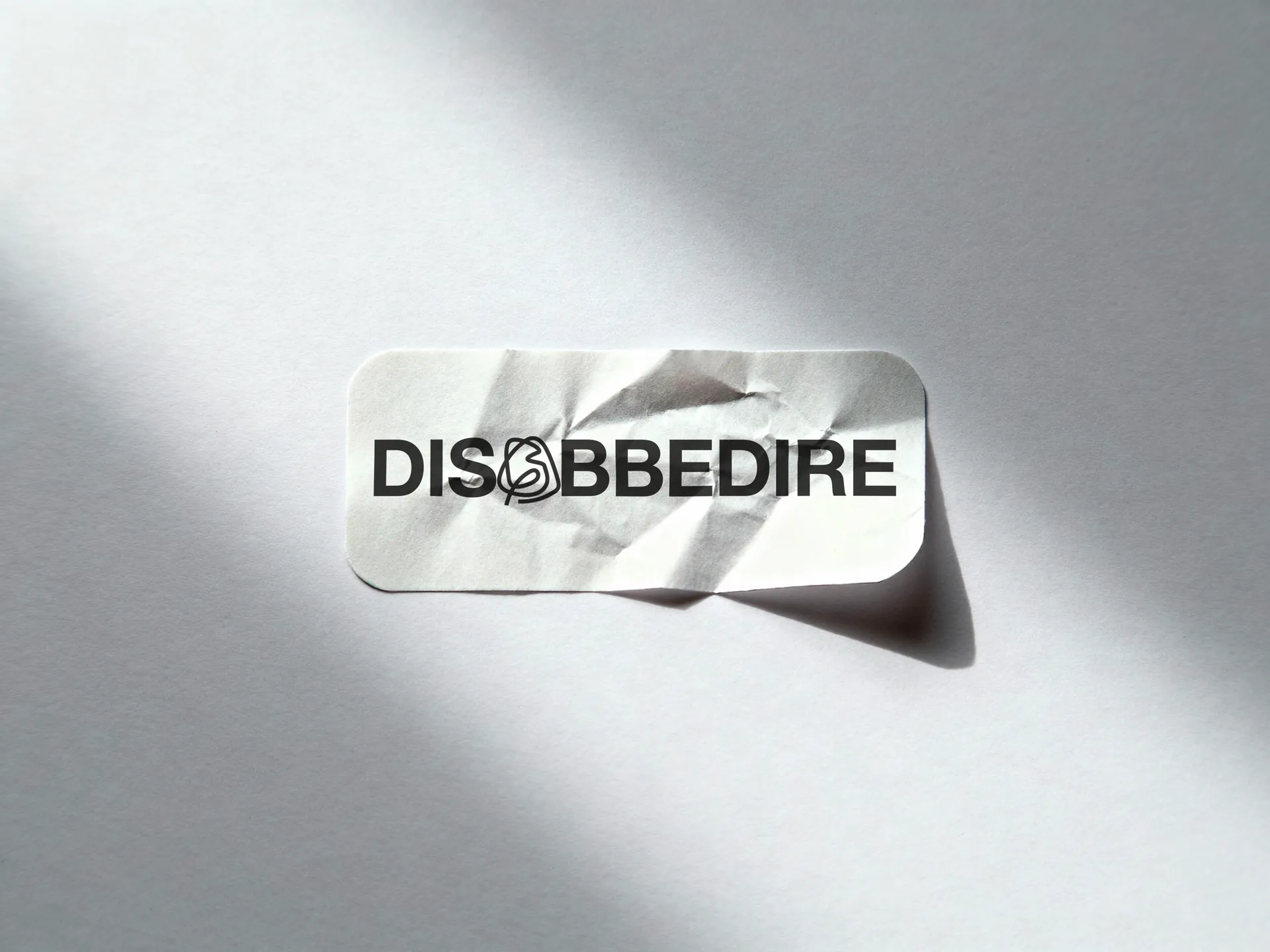 Identita Disobbedire, logotipo con il filo annodato nella O su adesivo
